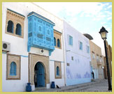 The streets of the medina at Kairouan UNESCO world heritage site (Tunisia) are lined with beautiful white-washed Arab-style buildings with decorative blue-painted balconies and shutters